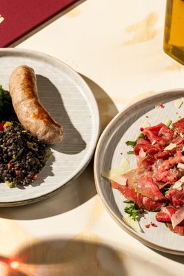 Beef carpaccio with rocket salad, lemon mayonnaise and pink pepper, fresh salsiccia with black lentil and kale salad, Barolo Giovanni Rosso 2021 – Amiata Tuscan restaurant Prague